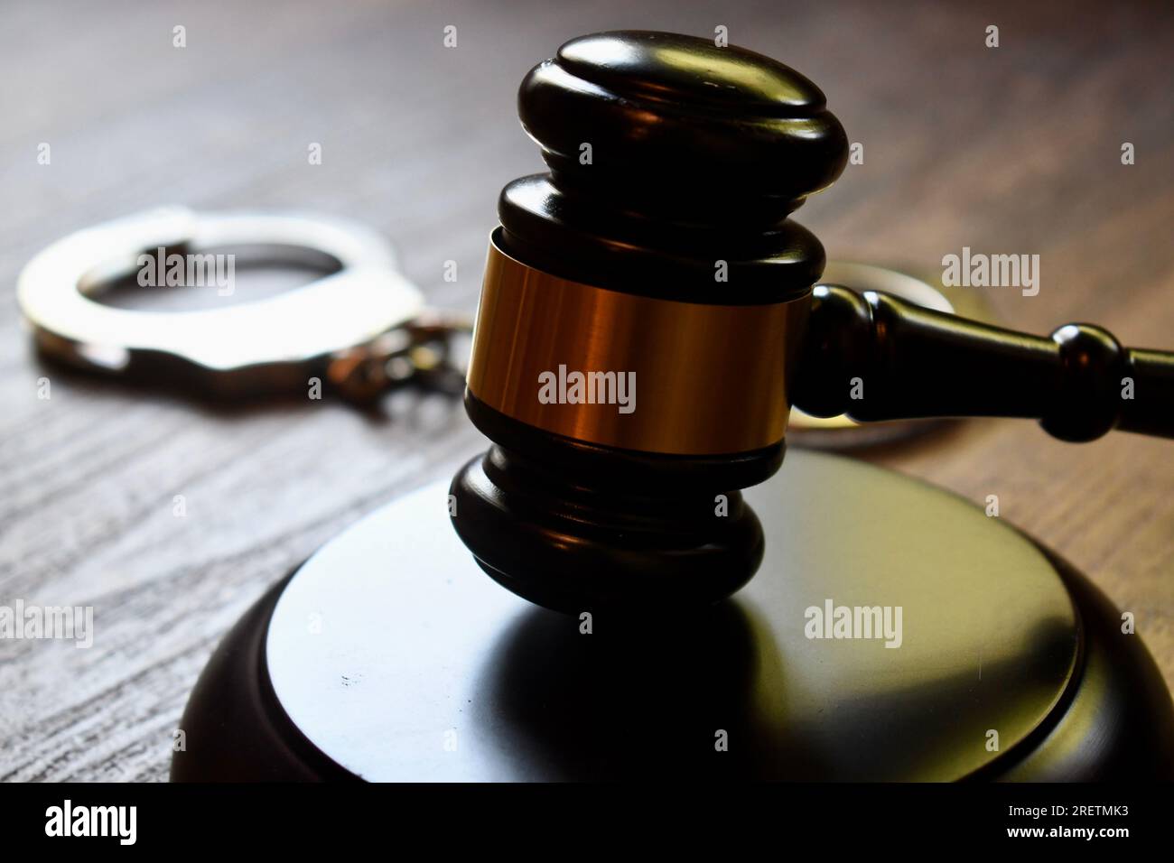 Judge’s gavel and block with handcuffs on a dark wooden table Stock Photo