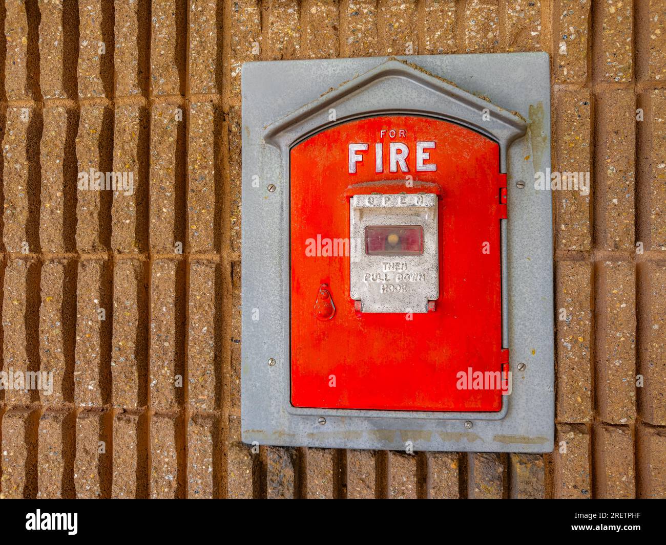 Vintage fire alarm red pull box mounted to the side of a municipal building in a city. background. Close up. Stock Photo