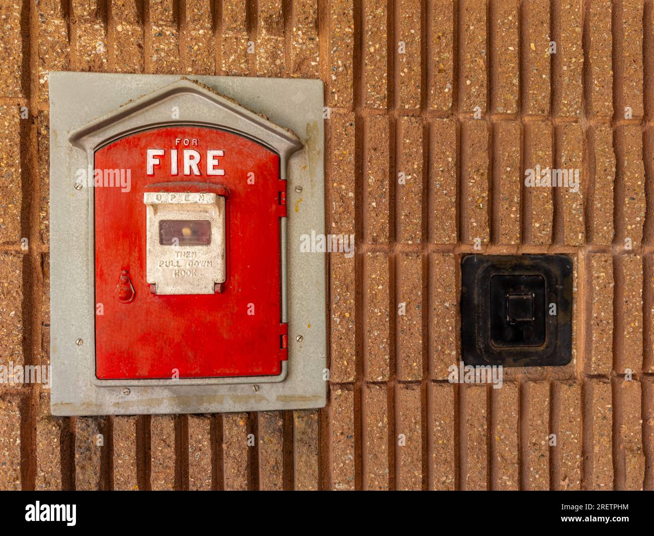 Vintage fire alarm red pull box mounted to the side of a municipal building in a city. background. Close up. Stock Photo
