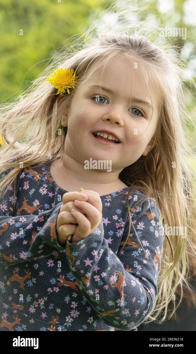 A smiling blond girl with a flower in her hair Stock Photo - Alamy