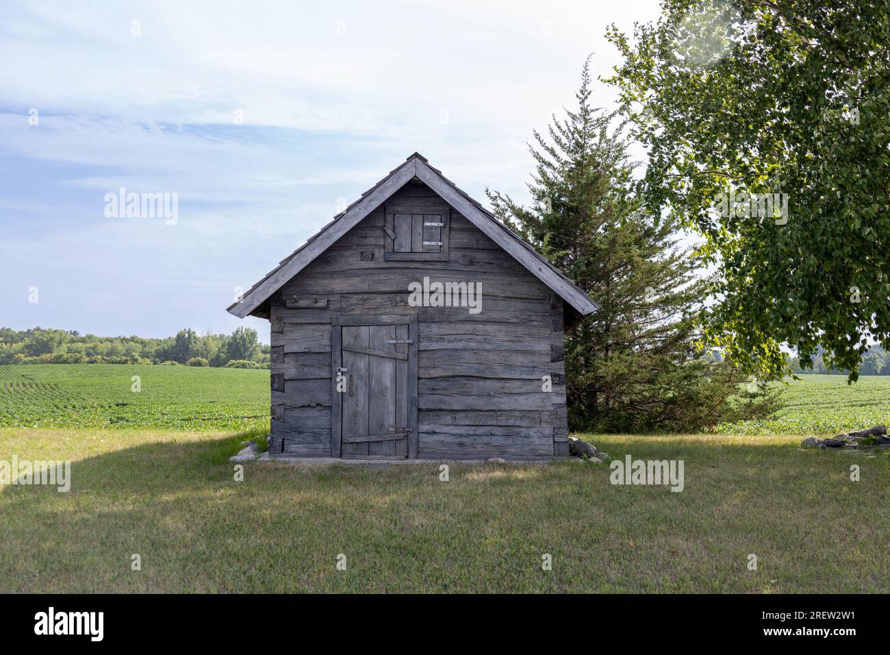 Sunny landscape view of a 19th century log cabin on the prairie in midwestern United States Stock Photo