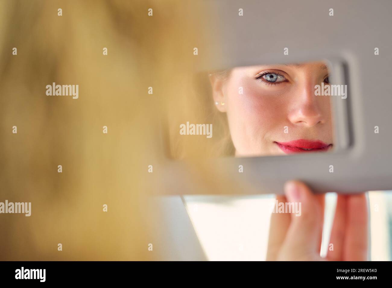 Crop attractive female wearing bright red lipstick looking in vanity