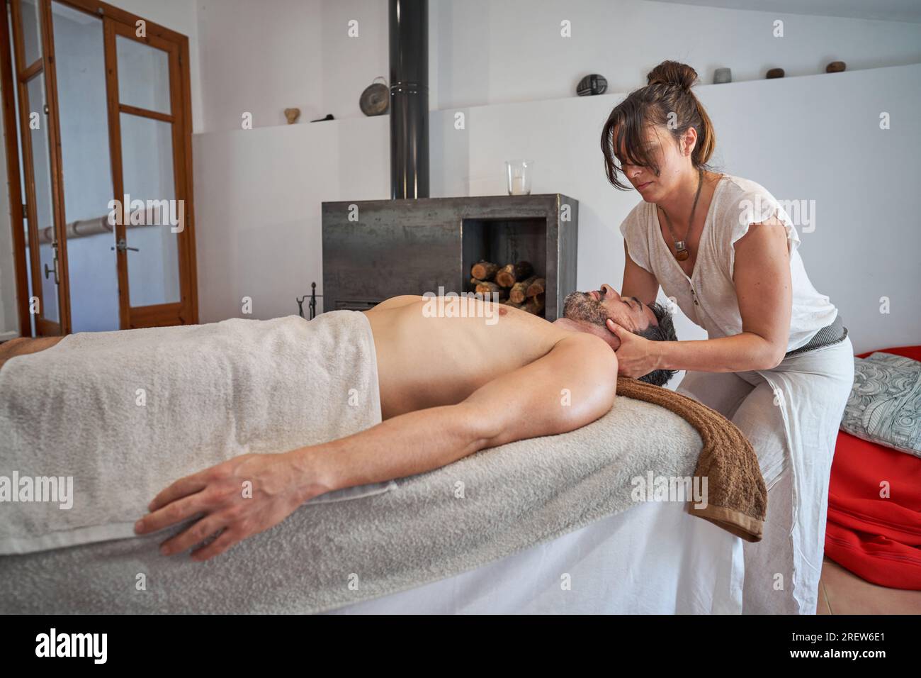 Concentrated adult female therapist rubbing neck of bearded male client  relaxing on table under towel with closed eyes during massage session at  room Stock Photo - Alamy