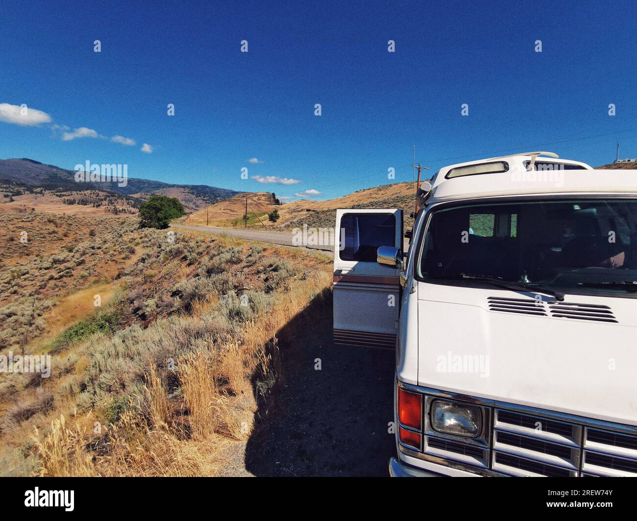 A parked camper van vehicle on a side of the road near Spotted Lake, located on Crowsnest HWY, Osoyoos British Columbia. Summer road trip journey in C Stock Photo