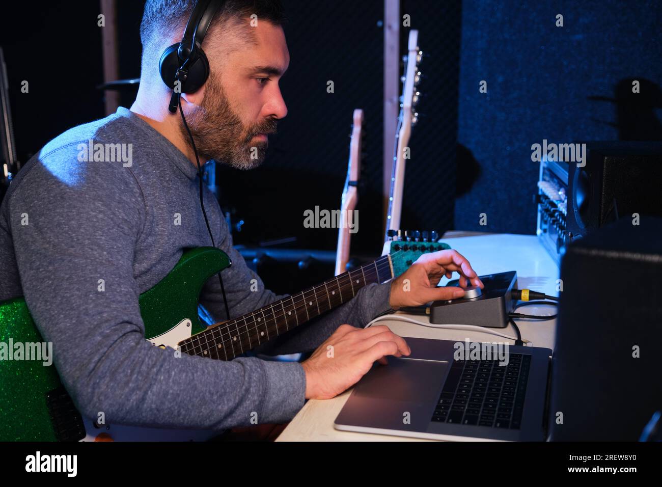 Musician adjusting the sound of his electric guitar with equalizer and