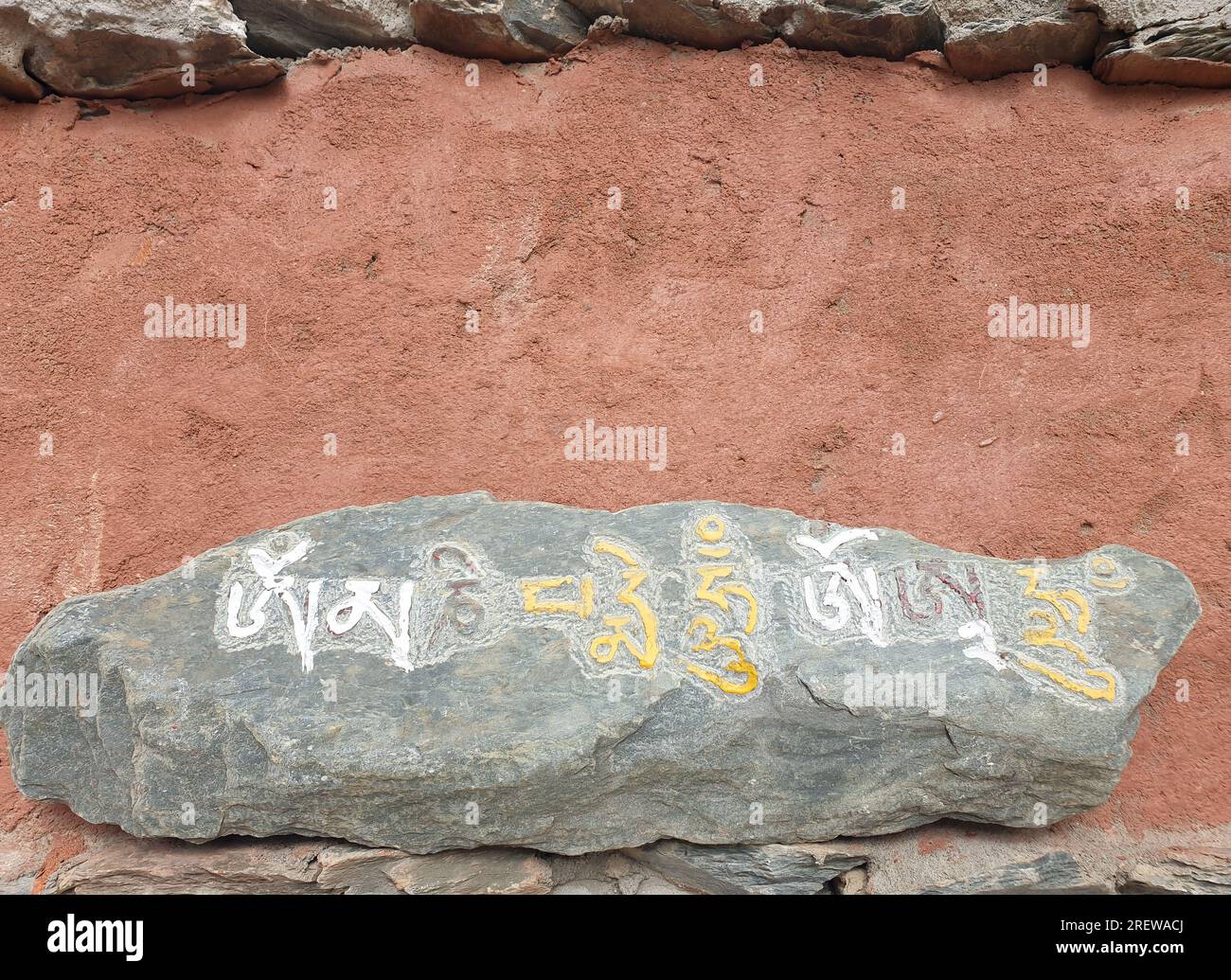 Mani stone placed on the wall. Carved stone with Tibetan script. Stock Photo