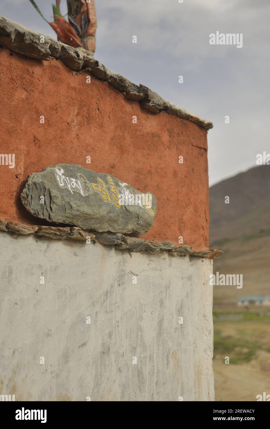 Mani stone placed on the wall. Carved stone with Tibetan script Stock ...
