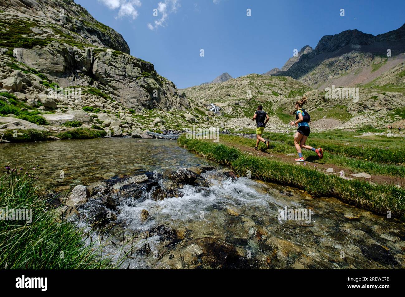 couple of mountain runners next to a river, Ibones azules and Bachimaña alto route, Huesca province, Spain Stock Photo