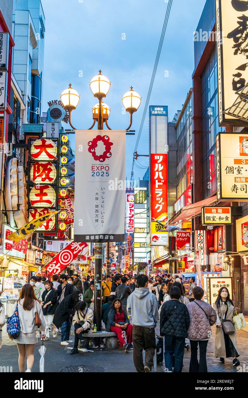 View along Dotonbori, early evening, busy with people. Foreground