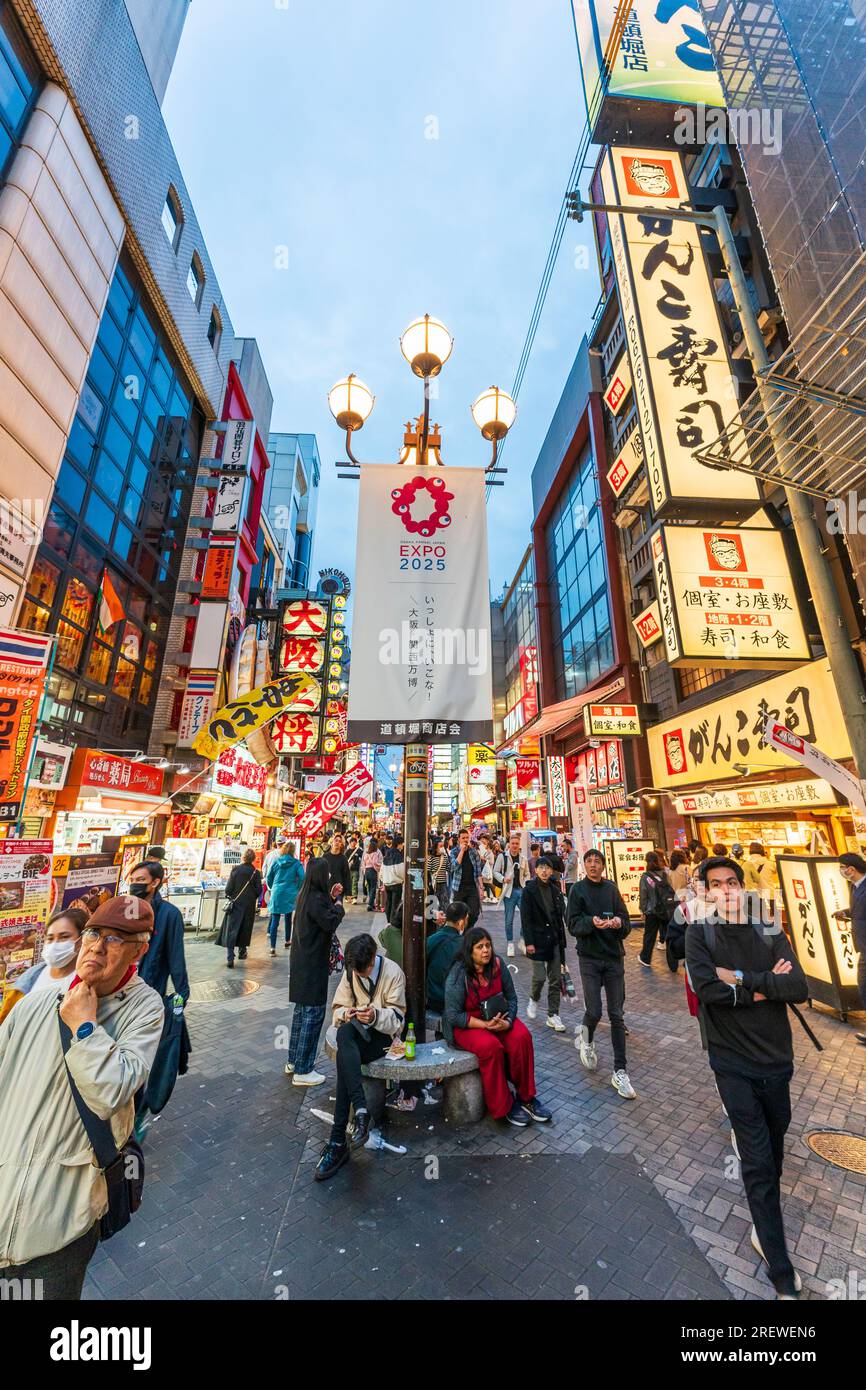 View along Dotonbori, early evening, busy with people. Foreground