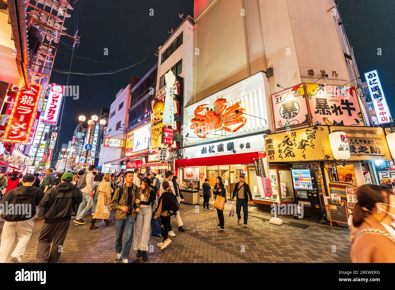 Night view along the busy crowded Dotonbori street with the popular Kani Doraku seafood restaurant with its large mechanical crab above the entrance. Stock Photo