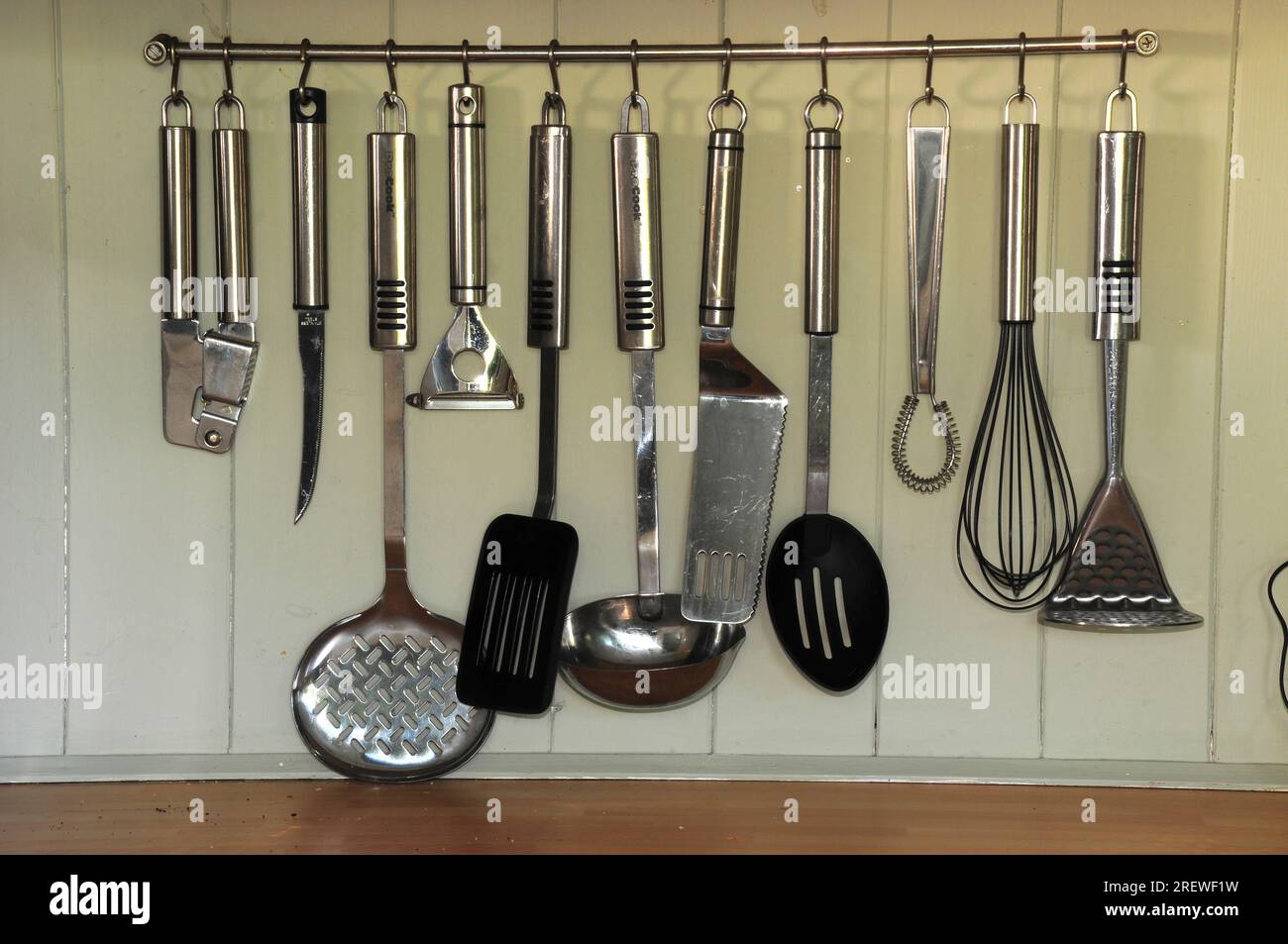 stainless steel kitchen utensils hanging in rack Stock Photo - Alamy