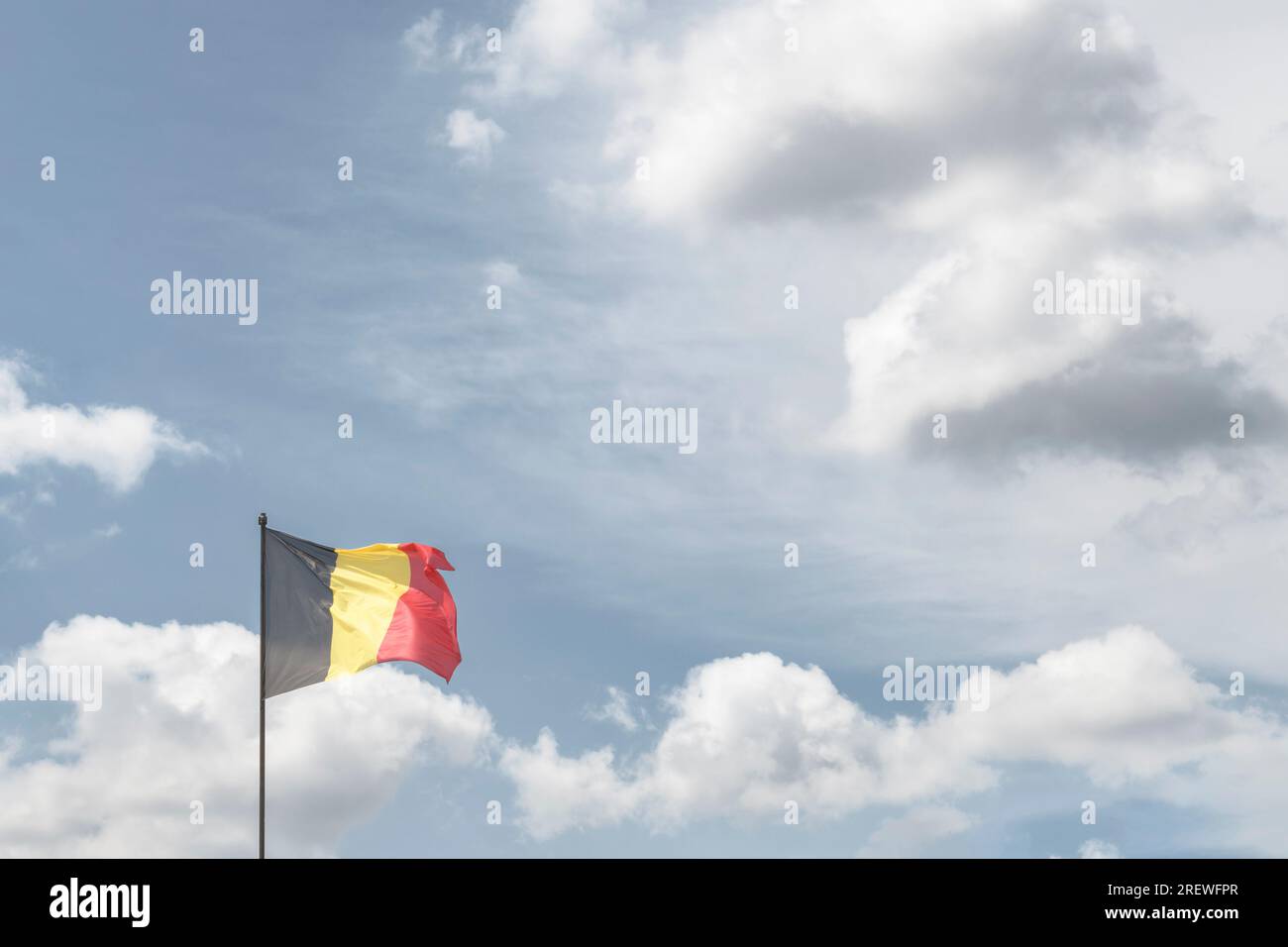 Belgian National Day. The national flag of the Kingdom of Belgium against the background of clouds in the sky. copy space Stock Photo