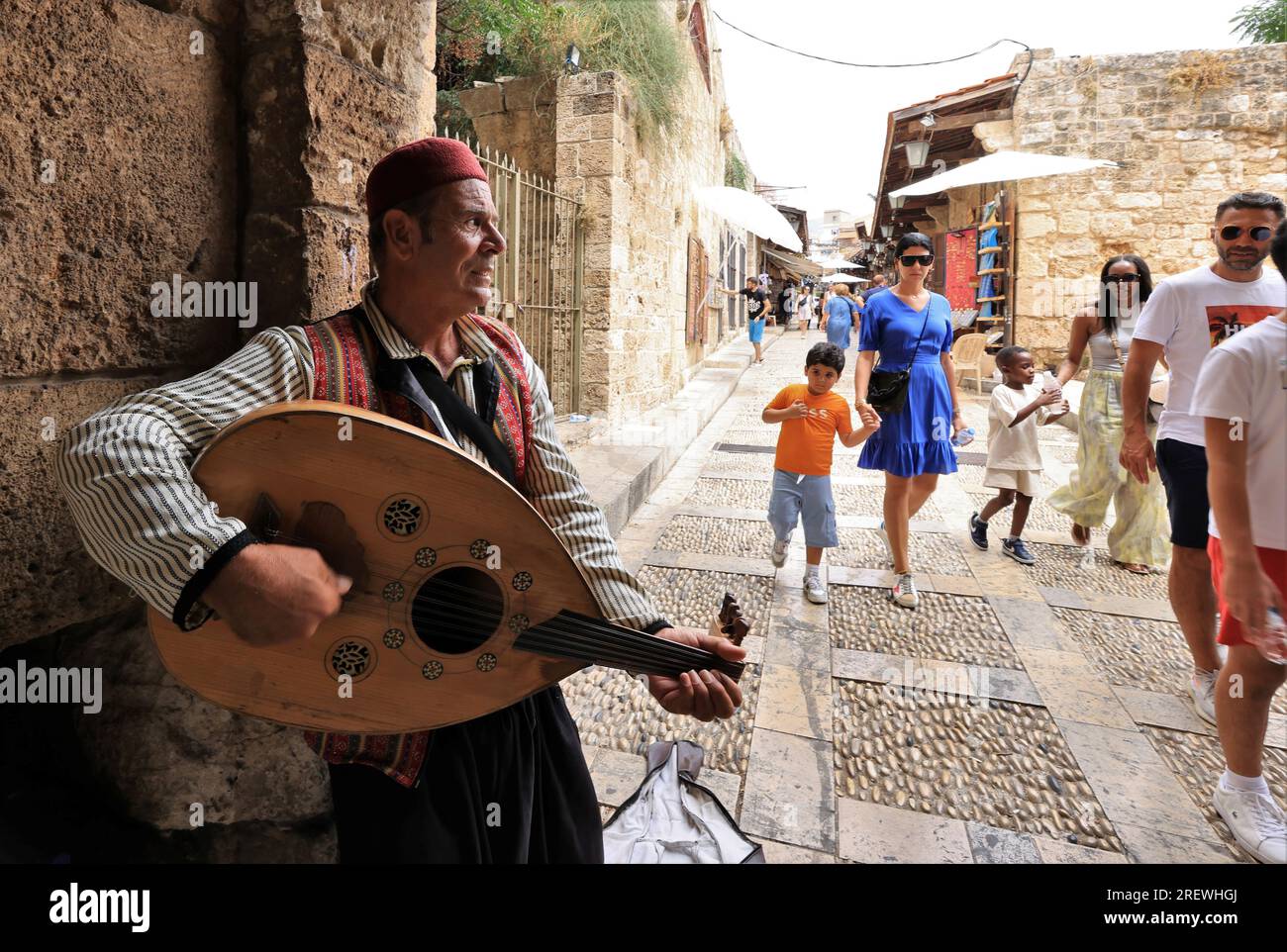 Beirut, Lebanon. 29th July, 2023. A busker performs as tourists walk by in Byblos, Lebanon, July 29, 2023. Lebanon's tourism season has exceeded all expectations, the National News Agency reported on Thursday, citing opinions of industry experts. Credit: Liu Zongya/Xinhua/Alamy Live News Stock Photo
