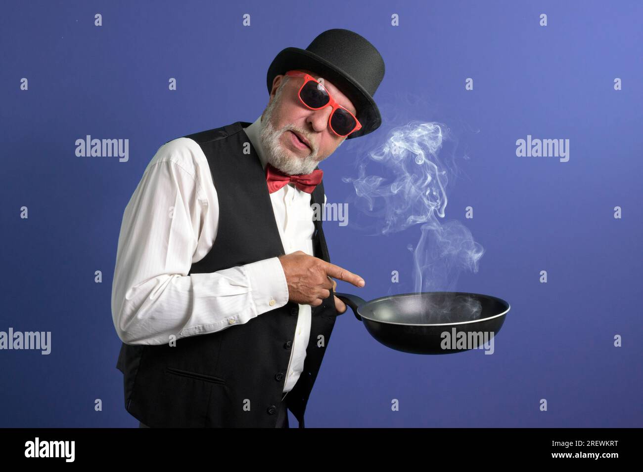 Don't forget about the kitchen. A man in festive attire with a smoky overheated frying pan calls for attention Stock Photo