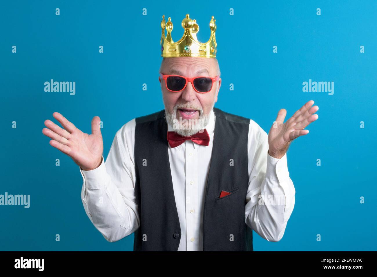 Funny old man in a festive suit with a bow tie and a golden crown on his head Stock Photo