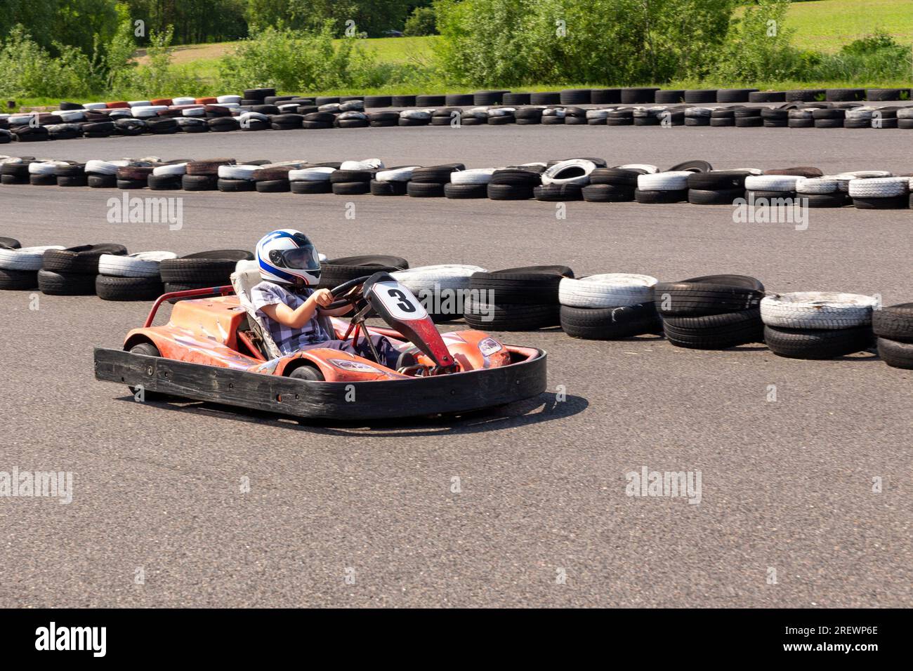 Youth Go Kart Racer on track. Dynamic image of teenage boy, moving fast by a go-kart, with motion blur effect. Stock Photo