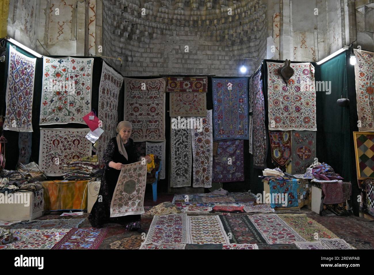 Old uzbek woman sell handmade carpets inside Abdoullaziz Khan madrasah