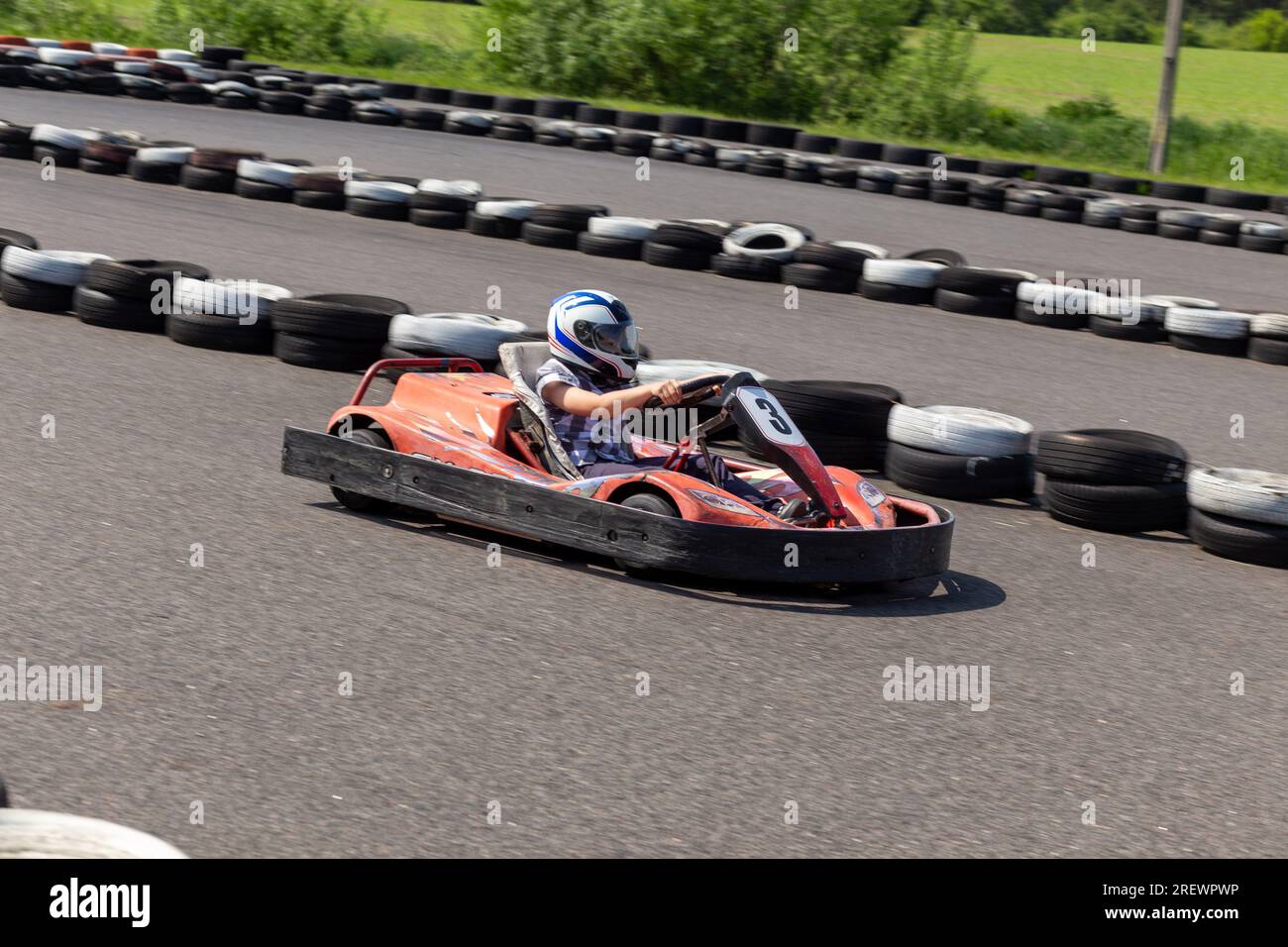 Youth Go Kart Racer on track. Dynamic image of teenage boy, moving fast by a go-kart, with motion blur effect. Stock Photo