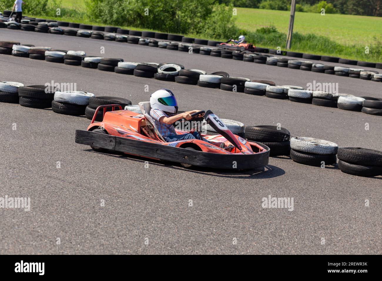 Youth Go Kart Racer on track. Dynamic image of teenage boy, moving fast by a go-kart, with motion blur effect. Stock Photo