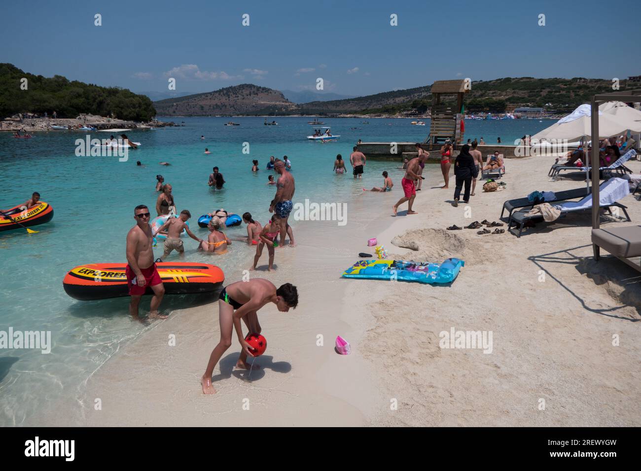 View of crowded beach in Ksamil, Albania with people swimming and having fun near 3 Ishujt resort. Tourists enjoying summer in Albanian destination Stock Photo