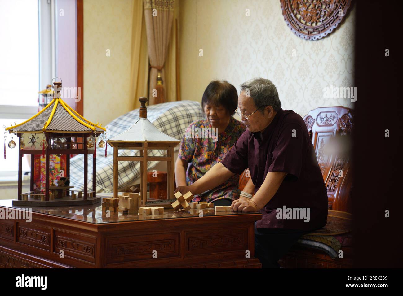 Shijiazhuang, China's Hebei Province. 30th July, 2023. Craftsman Hou Quanchen and his wife discuss the technique of making Kong Ming Lock in Shahe City, north China's Hebei Province, July 30, 2023. Hou, 79, has devoted himself for six decades to making Kong Ming Lock, a traditional Chinese folk educational toy. In his leisure hours, Hou also promotes the intellectual toy among school students. Credit: Mu Yu/Xinhua/Alamy Live News Stock Photo