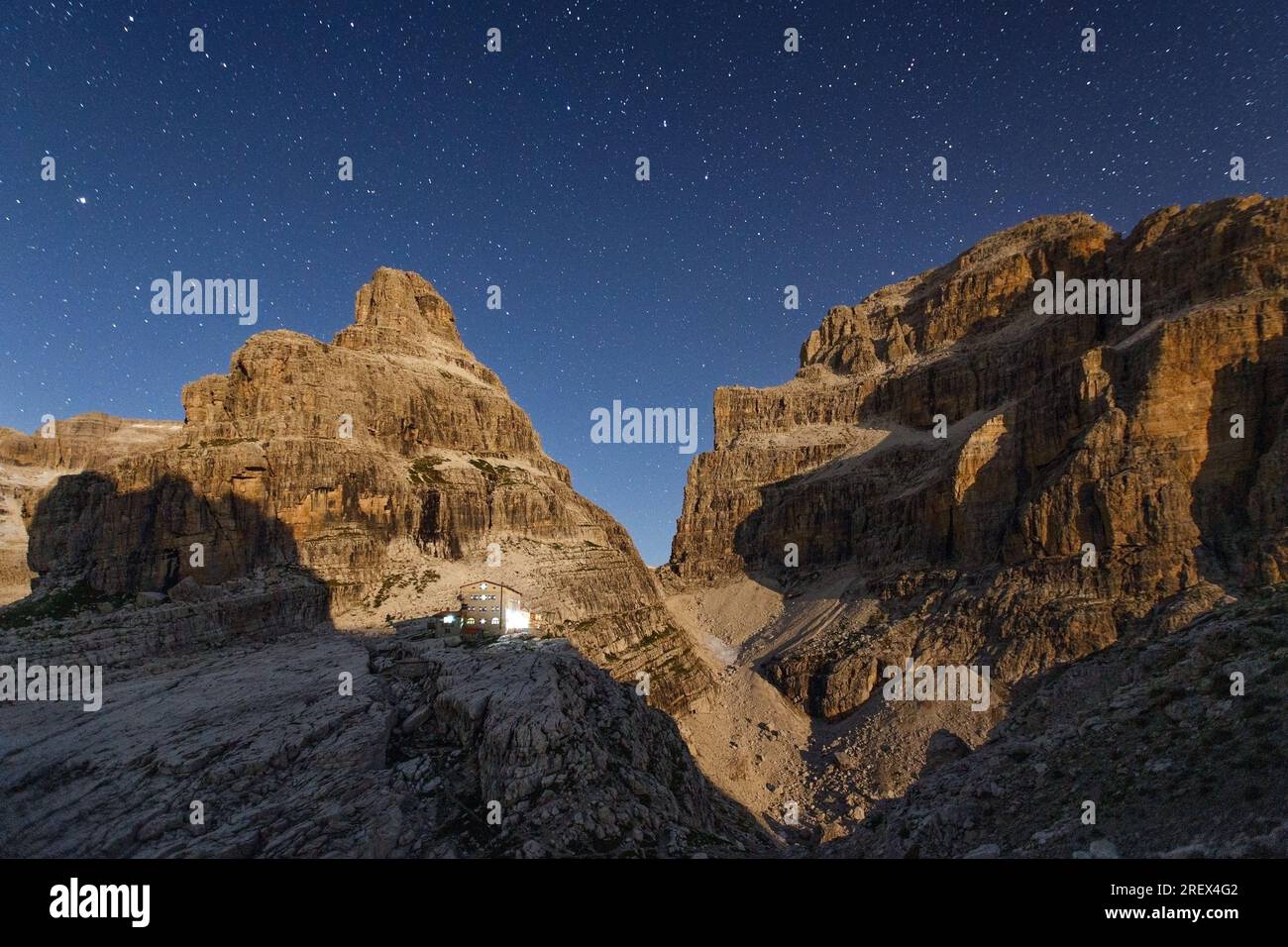 Moonlight as it rises. Starry sky. The Brenta Dolomites. Cima Brenta alta e bassa. Lights of Tosa Pedrotti refuge. Trentino. Italian Alps. Europe. Stock Photo