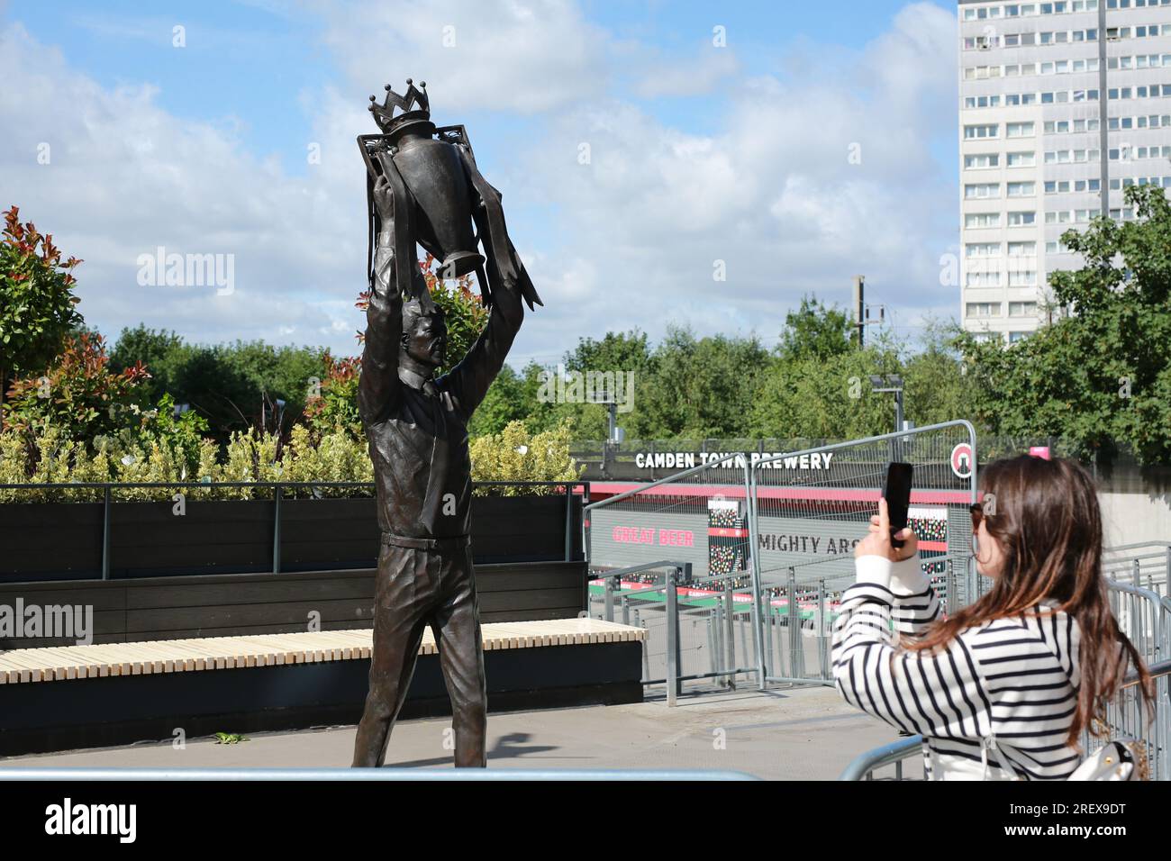 London, UK. 30 July 2023. Arsenal unveil Arsène Wenger statue outside the Emirates Stadium to commemorate the Gunners iconic manager's 22-year tenure at the club. The legendary manager led Arsenal FC to three Premier League titles, including the famous Invincibles season in 2003/04 where his side remained unbeaten, and seven FA Cups. The bronze statue, which was created by sculptor Jim Guy, is 3.5 metres high and weighs approximately half a tonne, and depicts the former French manager lifting the Premier League trophy. Credit: Waldemar Sikora/Alamy Live News Stock Photo