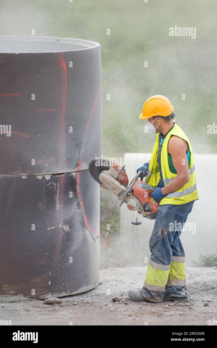 A worker cuts concrete with a special saw. The process of cutting a