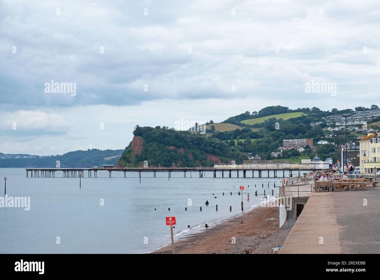 Teignmouth, England – July 21, 2023: Landscape view of the Devon resort town’s promenade, beach and Victorian pier facing the English Channel Stock Photo