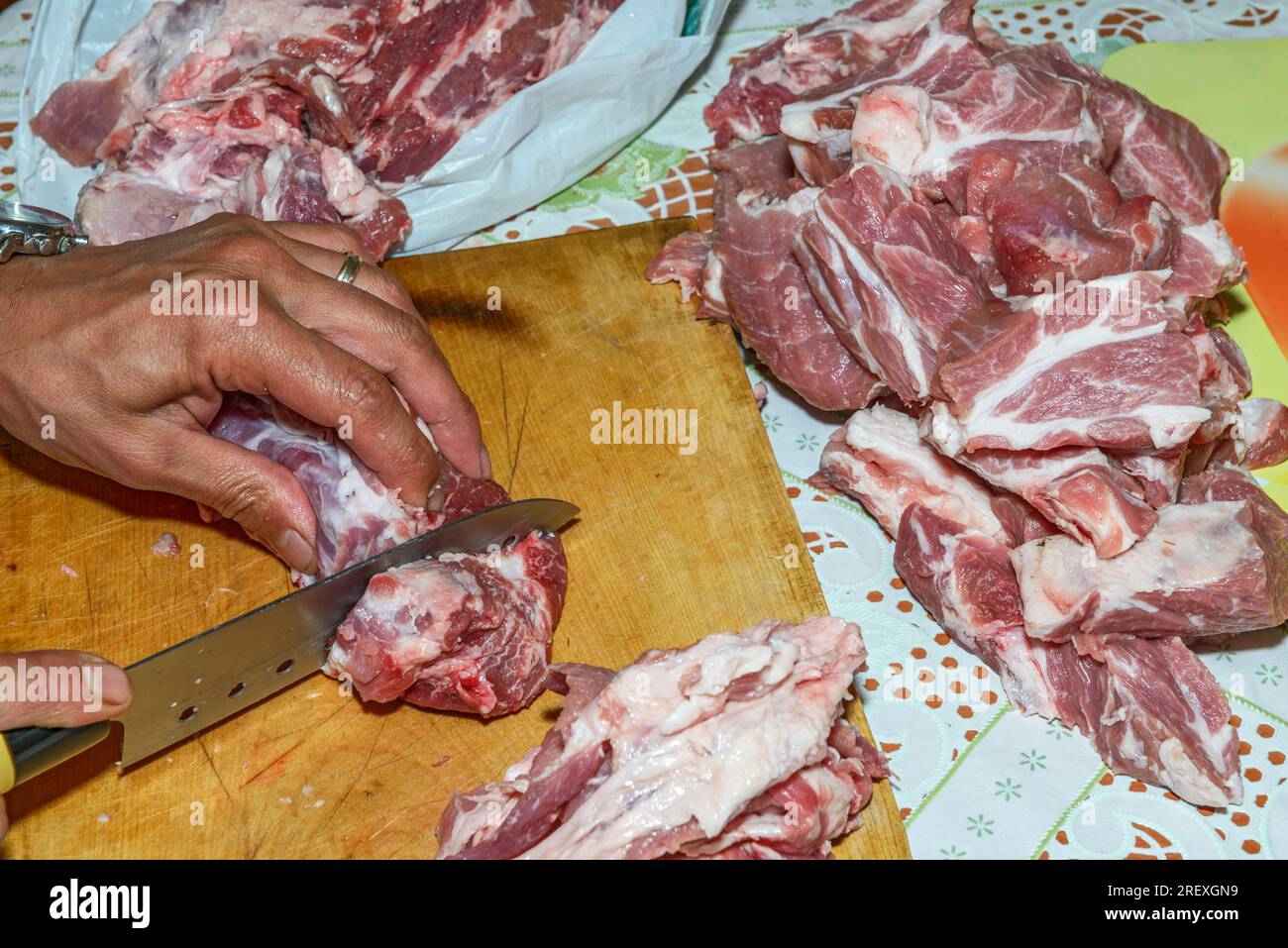 Hands of man that is slicing up big piece of raw meat into smaller pieces  by sharp knife Stock Photo - Alamy
