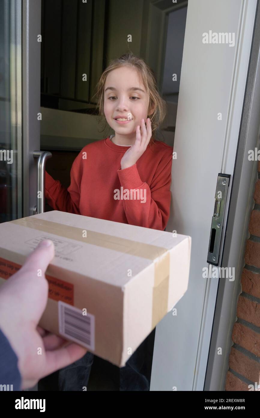 Girl opens the door to a postman with a package. lifestyle Stock Photo