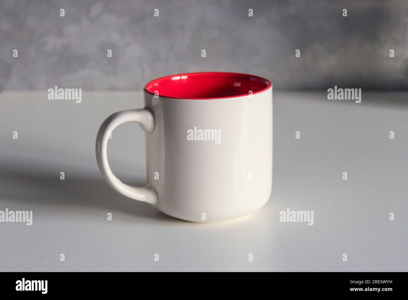 White ceramic tea cup red inside on the kitchen table Stock Photo