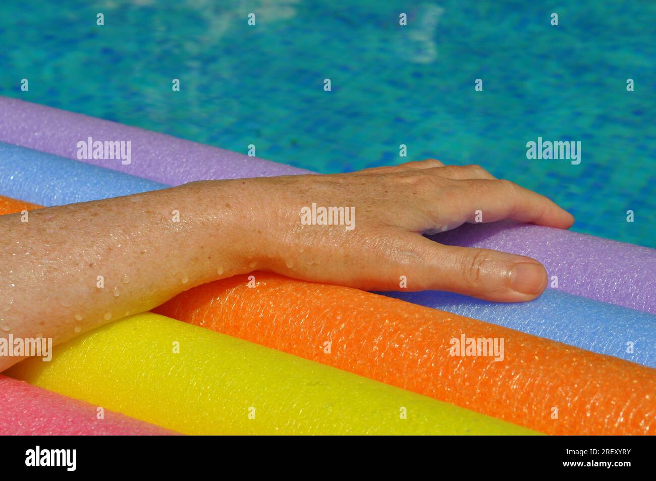 Rainbow coloured floating foam sticks and female hand, in swimming pool  Stock Photo - Alamy