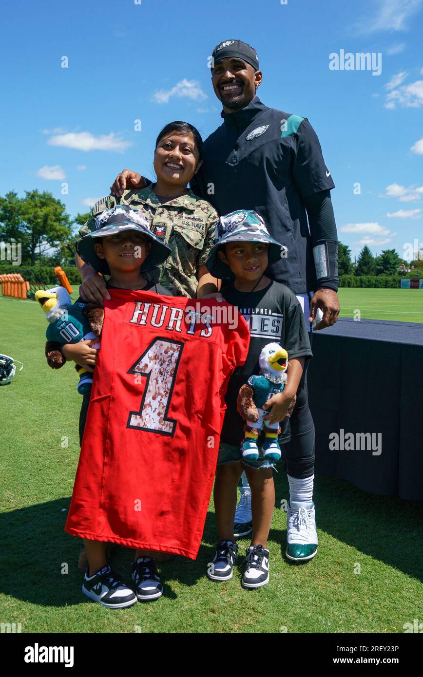 Philadelphia Eagles' Jalen Hurts, right, poses with the fan who received  his signed practice jersey with her two twins during practice at an NFL  football training camp, Sunday, July 30, 2023, in