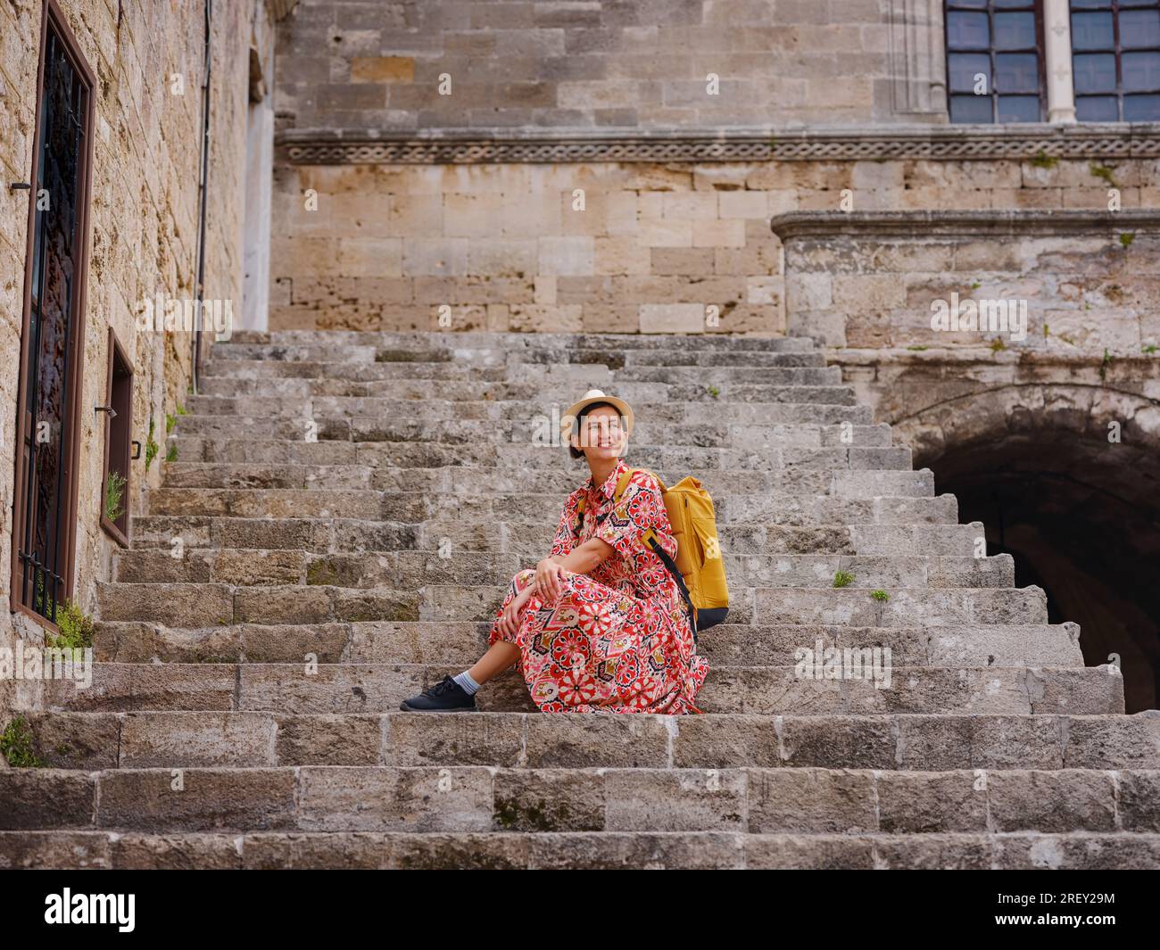 Rhoades Steps Young Asian woman in red dress walks through streets of Rhodes. woman ...