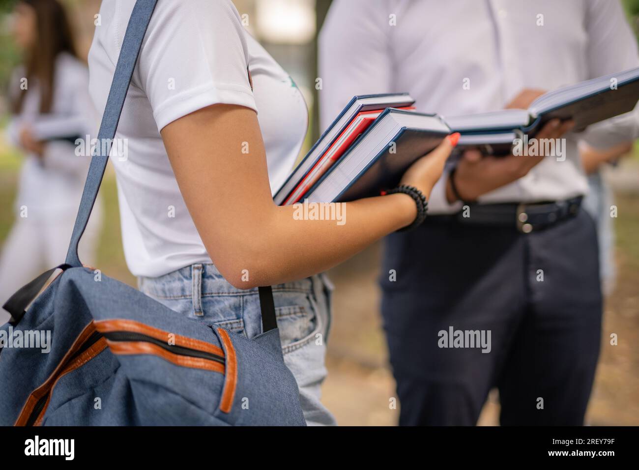 Two students in uniforms holding books and notebooks in their hands ...