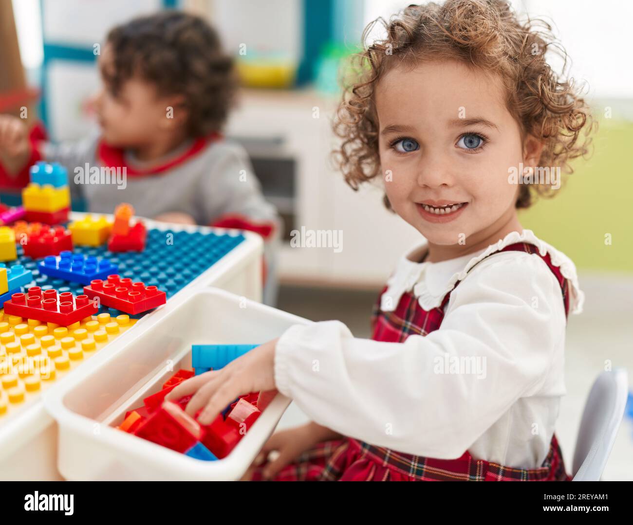 Adorable girls playing with construction blocks sitting on table at