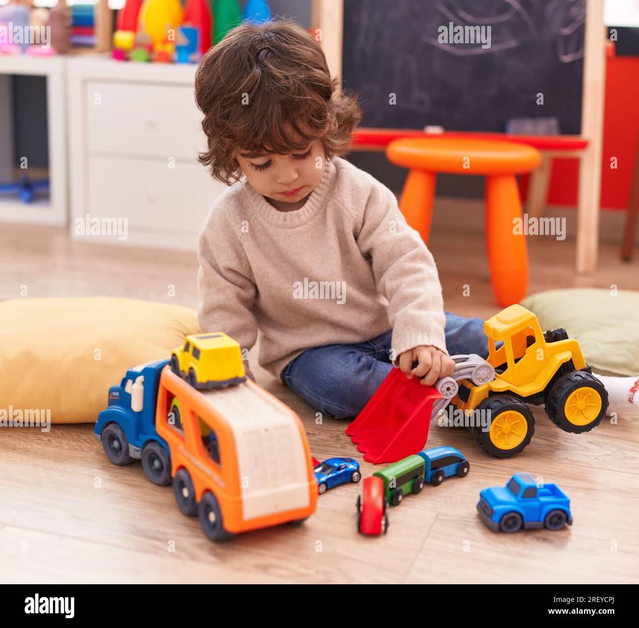 Adorable hispanic boy playing with car toy sitting on floor at ...