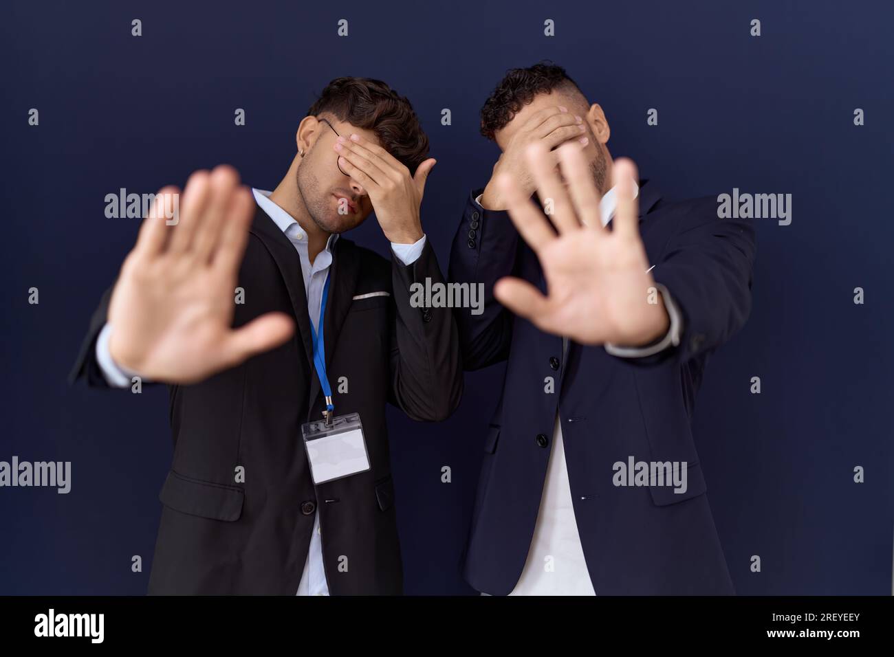 Two hispanic business men wearing business clothes covering eyes with hands and doing stop gesture with sad and fear expression. embarrassed and negat Stock Photo