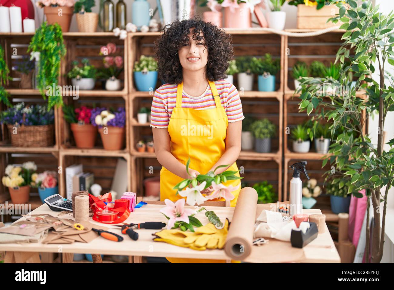 Young middle eastern woman florist make bouquet of flowers at florist ...