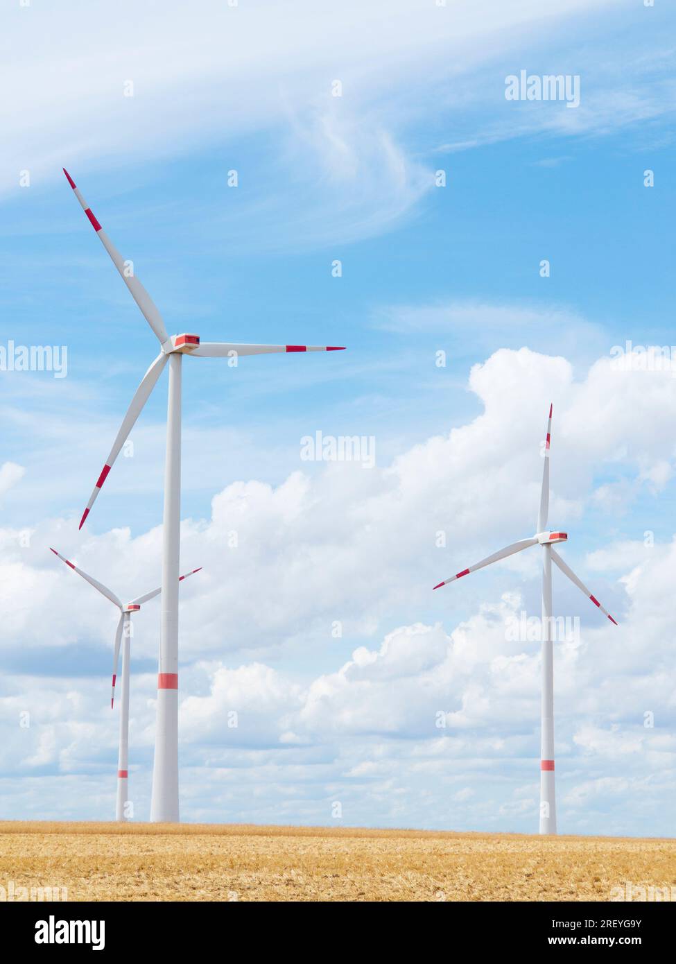 Wind turbine in front of bright blue sky with white clouds Stock Photo ...