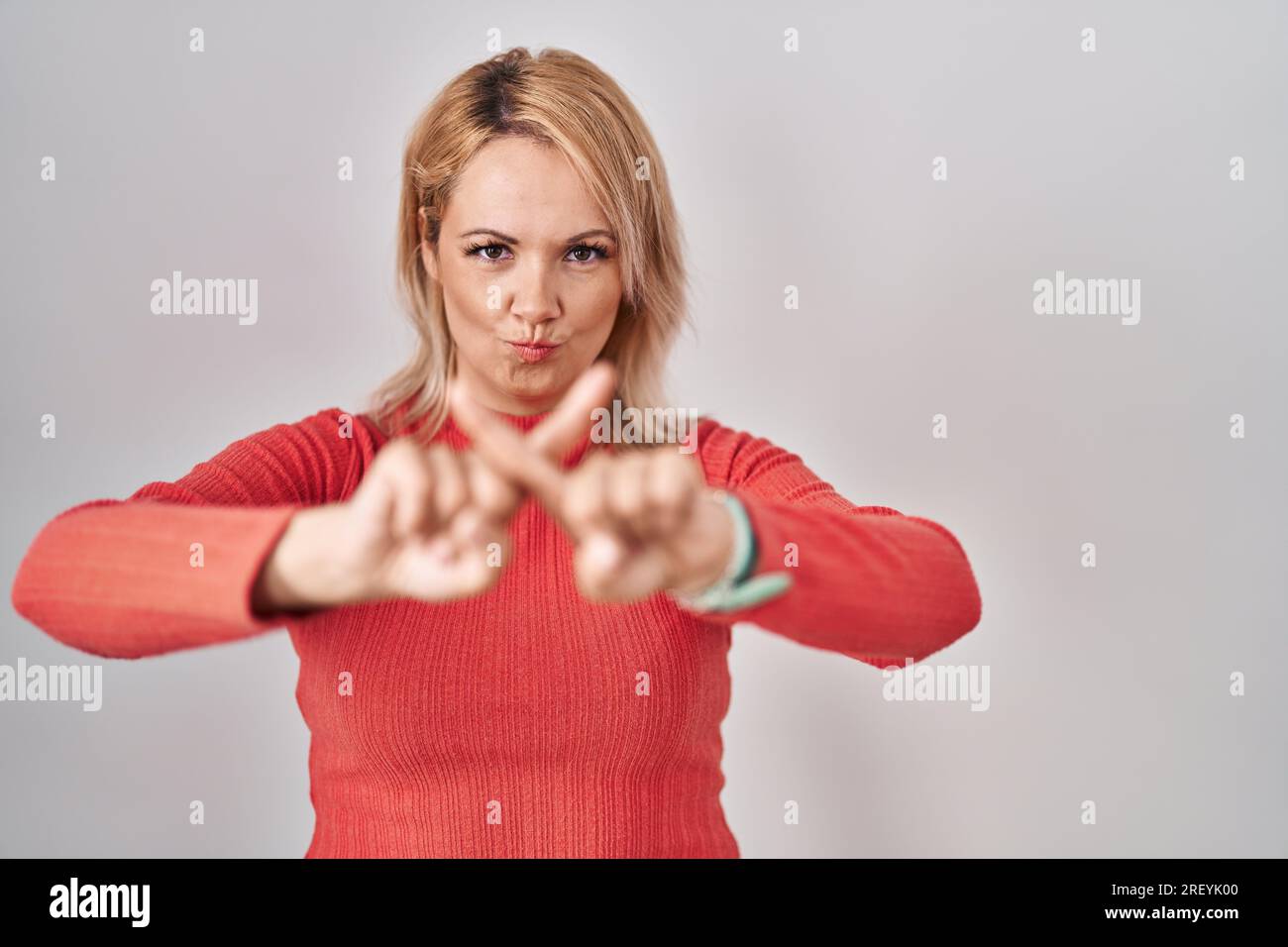 Blonde woman standing over isolated background rejection expression ...