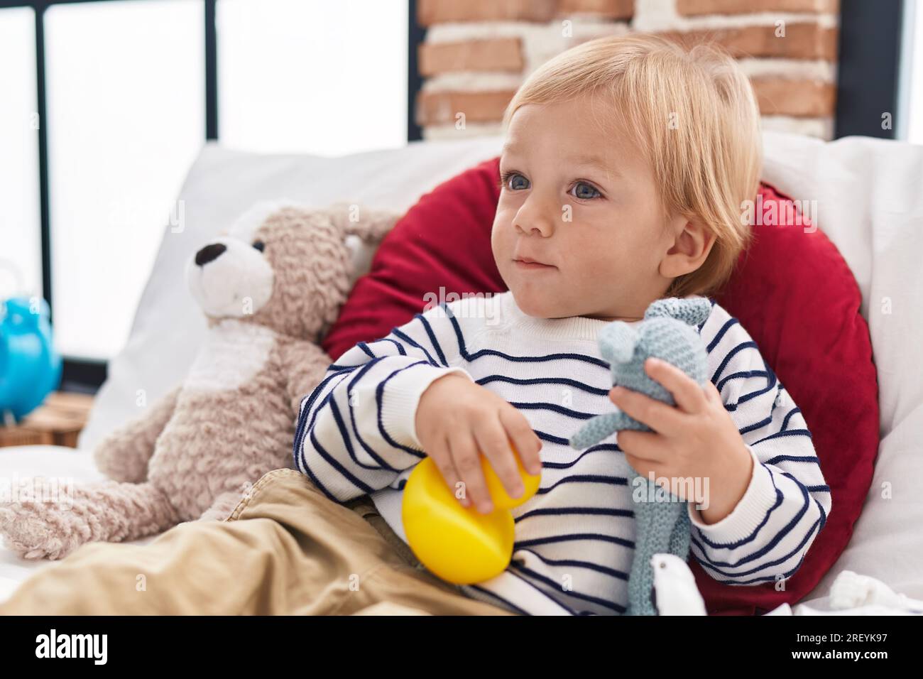 Adorable caucasian boy holding doll sitting on bed at bedroom Stock ...