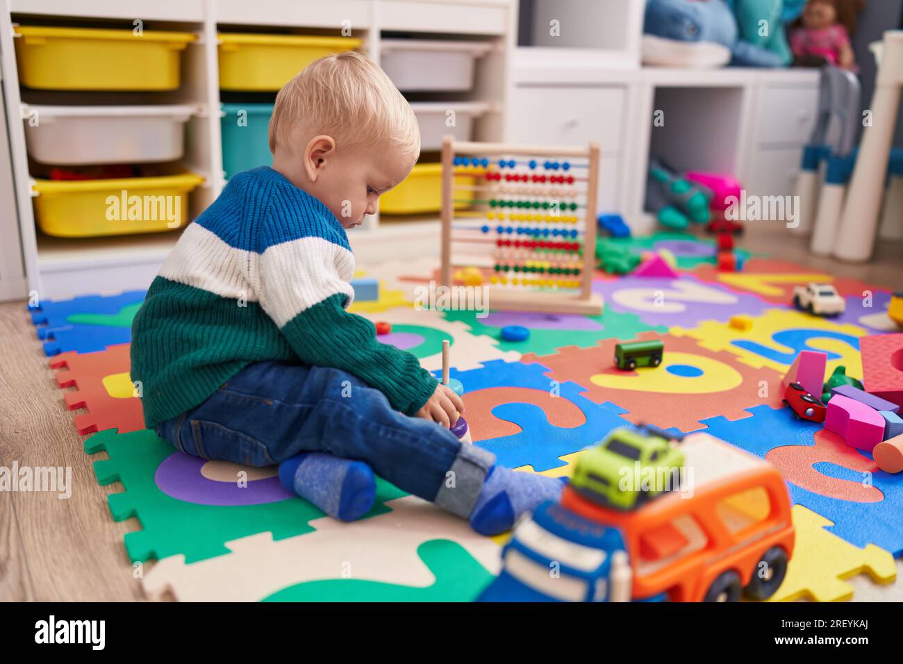 Adorable caucasian boy playing with car toy sitting on floor at ...