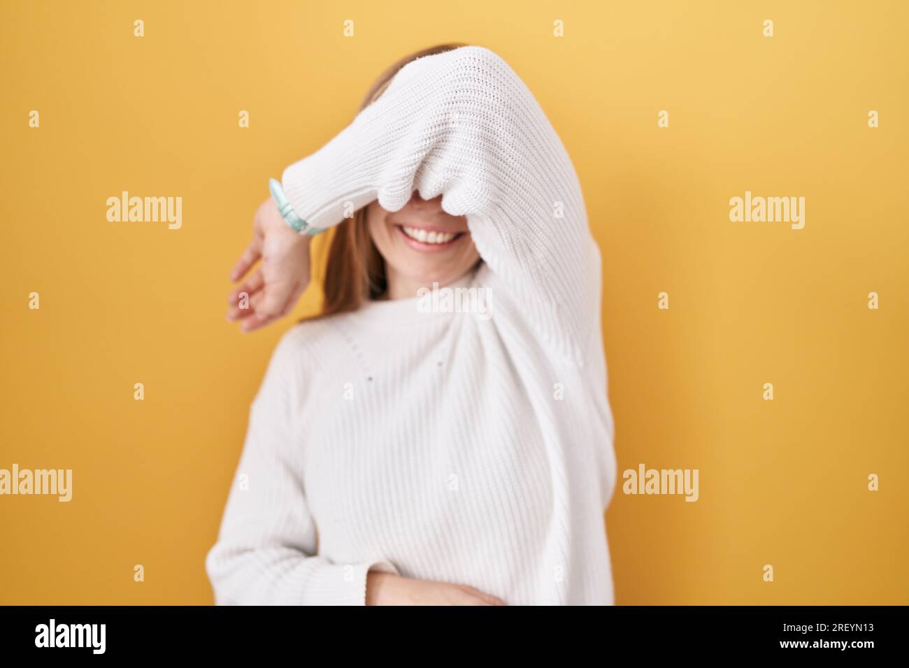 Smiling Reyn Young caucasian woman wearing white sweater over yellow background ...