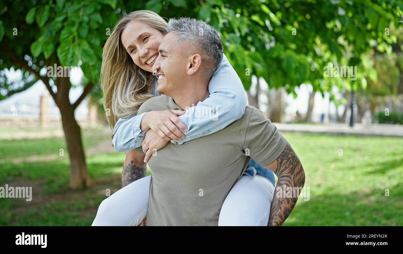 Smiling Reyn Man and woman couple smiling confident holding girlfriend on back at ...
