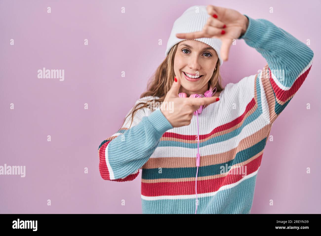 Smiling Reyn Young blonde woman standing over pink background smiling making frame ...
