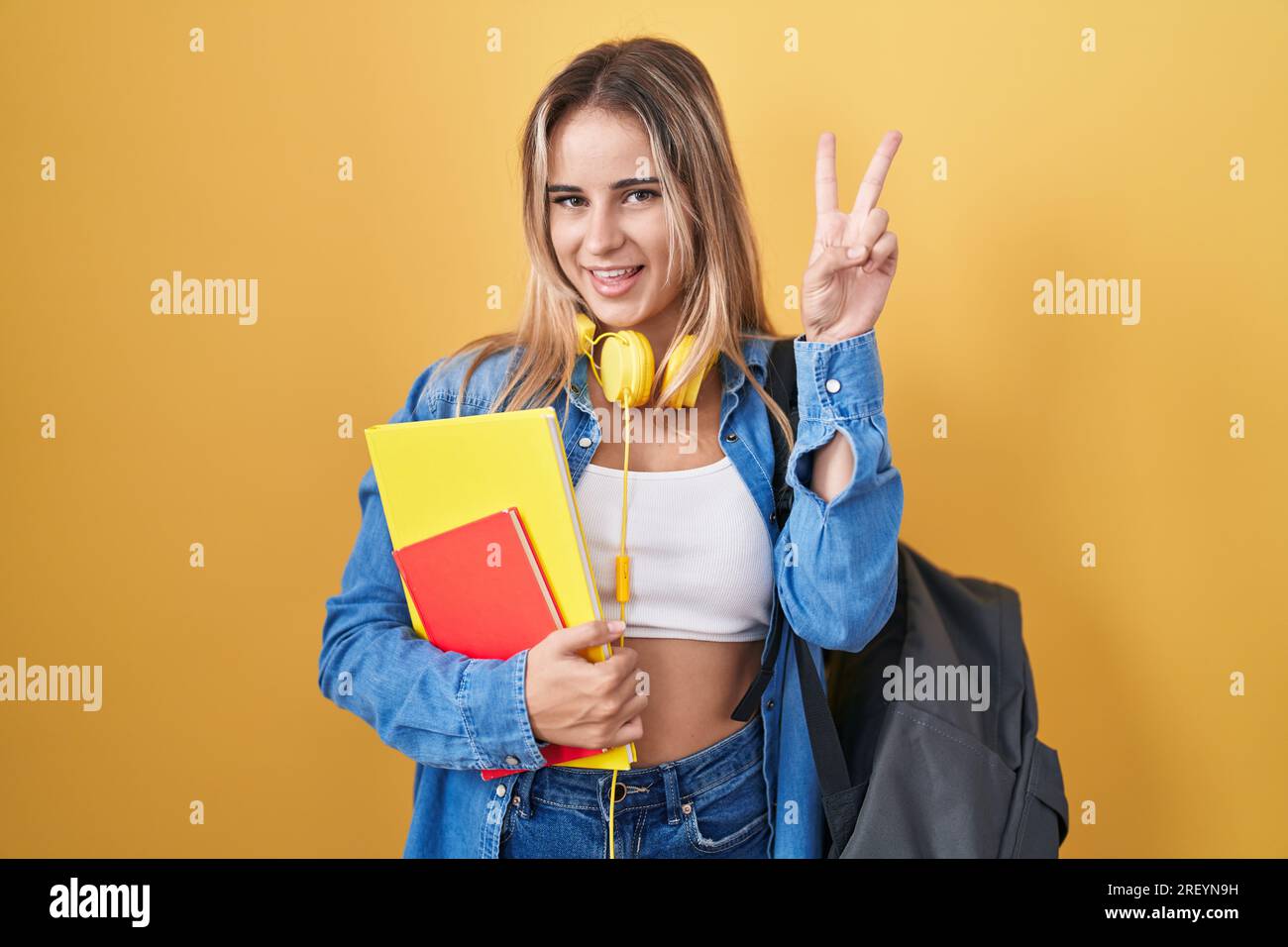 Smiling Reyn Young blonde woman wearing student backpack and holding books smiling ...