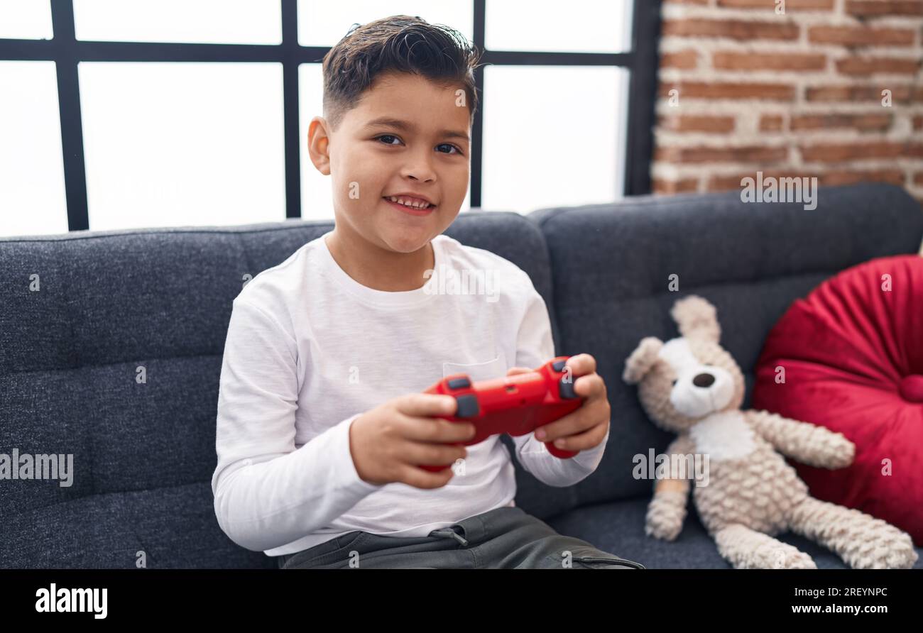 Adorable hispanic boy playing video game sitting on sofa at home Stock ...